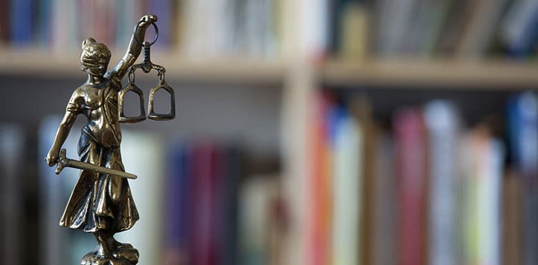Justice statue in front of shelves of law books